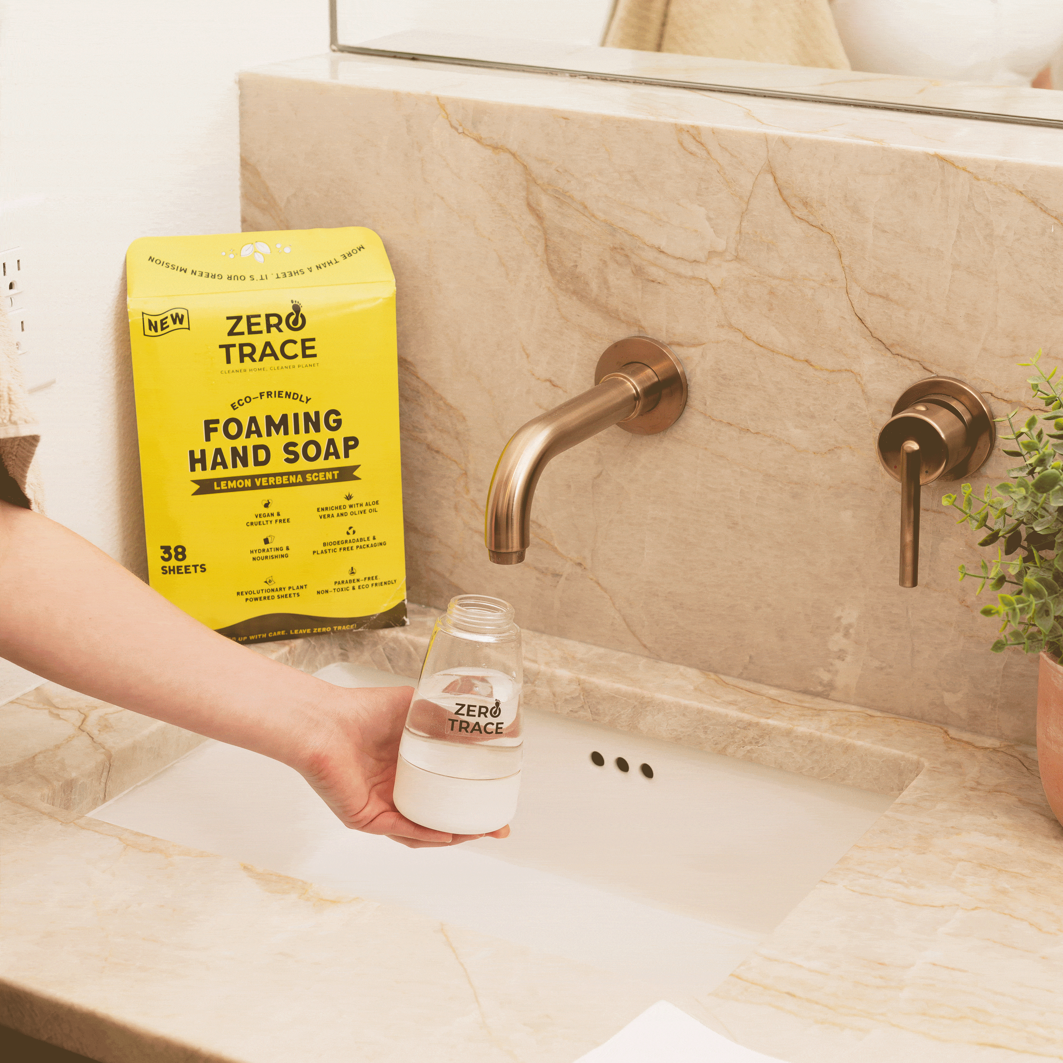 An eco-friendly person is holding a bottle of Zero Trace Hand Soap Sheets in front of a sink.