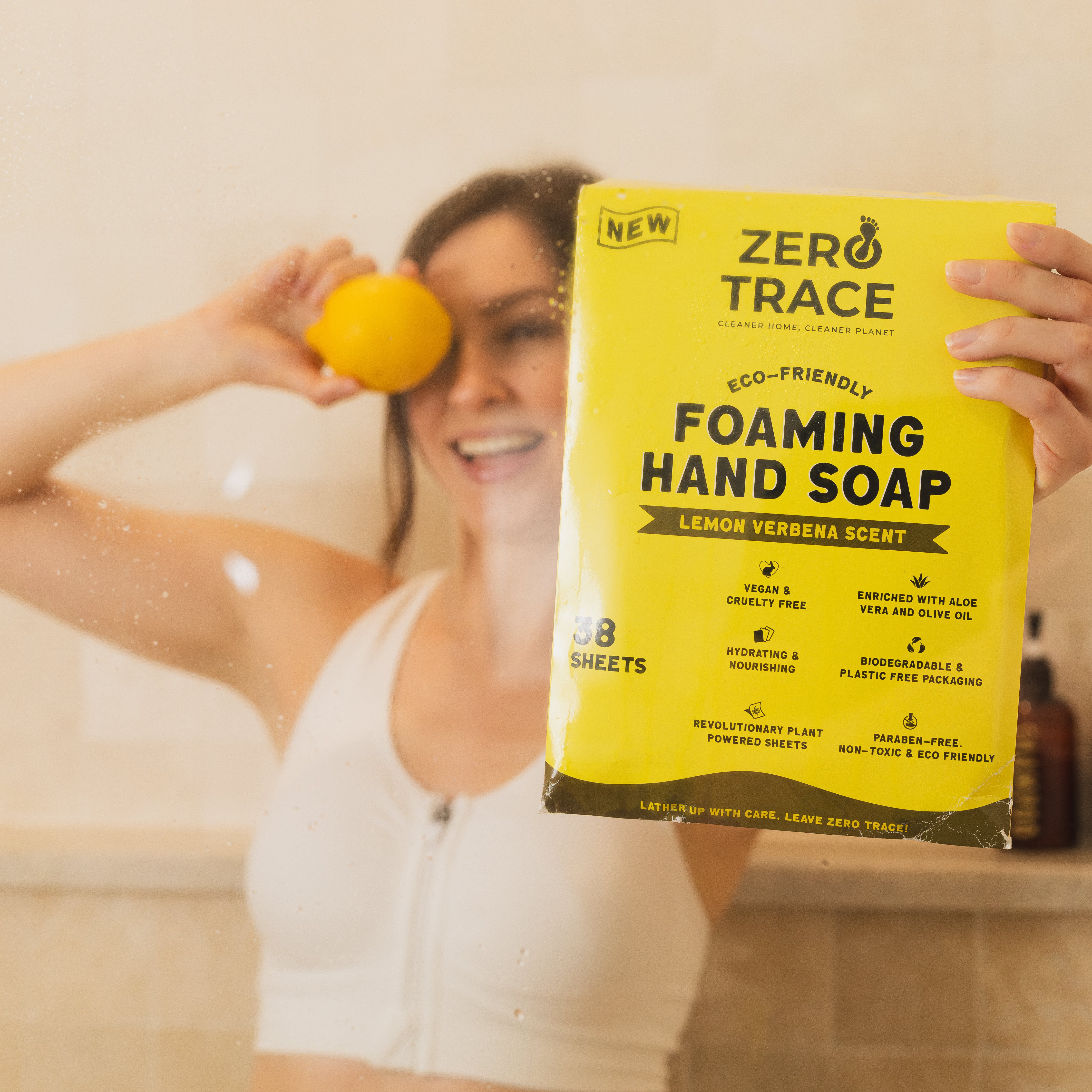 A woman holding up a box of Zero Trace Hand Soap Sheets.
