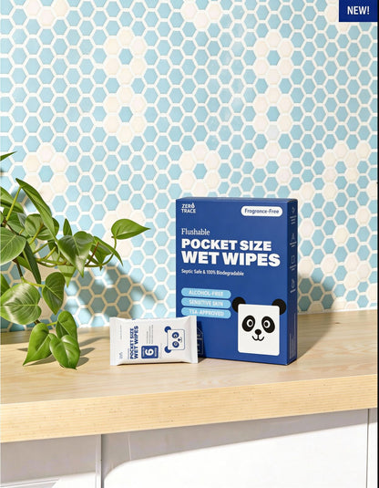 A box and packet of Zero Trace FLUSHABLE MINI WIPES, featuring a panda logo, sit on a white countertop in front of a blue hexagonal tile wall.